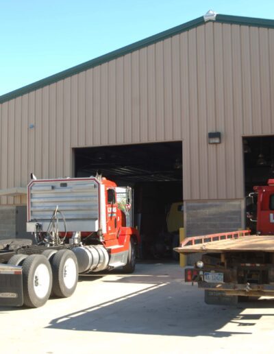 Semi-trucks undergoing maintenance in an industrial garage facility.