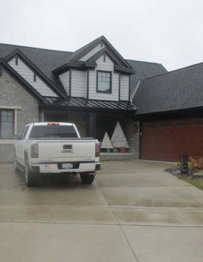 A truck parked in the driveway of a modern two-story house on a cloudy day.