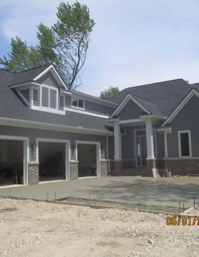 Newly constructed house with open garage and unfinished landscaping, dated june 1, 2021.