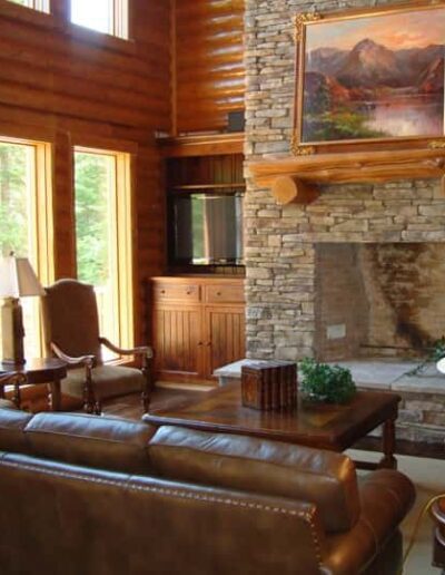 Cozy living room with leather furniture, a stone fireplace, and wooden accents.